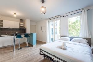 a bedroom with a large bed and a kitchen at Blue Pearl By Plaza in Montévrain