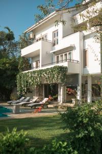 a large white building with lounge chairs in the yard at Arahtis Lake Villa in Hikkaduwa