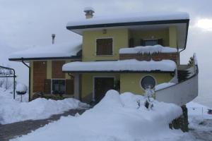 a house with a pile of snow in front of it at Casa Belvedere in Tenna 