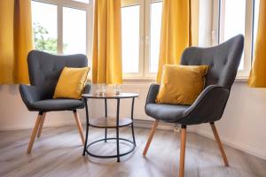 two chairs and a table in a room with yellow curtains at Loh9 - Das Apartment im Citycenter - Parkplatz - Wlan - Aufzug in Chemnitz