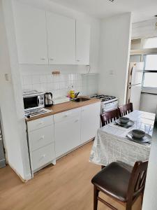 una cocina con armarios blancos y una mesa con sillas. en Уютная квартира в Кирьят-ям, en Qiryat Yam