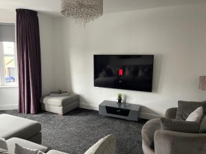 sala de estar con TV de pantalla plana en la pared en Holdsworth House Apartments en Killingbeck