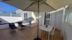 eine Terrasse mit einem Sonnenschirm, einem Tisch und Stühlen in der Unterkunft Casa Ila Flower Beach in Playa Honda