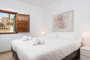 - une chambre blanche avec un grand lit et une fenêtre dans l'établissement Maca Sol, adosado con vistas a la montaña, à Campanet