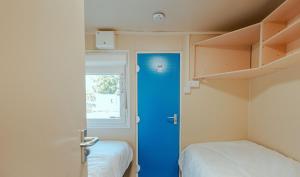 a room with a blue door and two beds at IOMTT Village at Isle of Man TT in Douglas