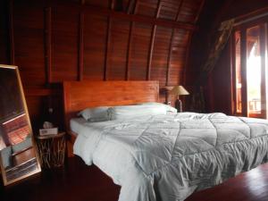 een slaapkamer met een groot bed met een houten hoofdeinde bij Candra Homestay Besakih in Besakih