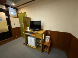 a room with a television on a desk with a door at ホテルカスカベ Hotel Kasukabe in Kasukabe