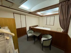 a bathroom with a tub and two chairs and a table at ホテルカスカベ Hotel Kasukabe in Kasukabe