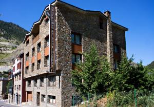 un bâtiment en briques avec un arbre devant lui dans l'établissement Apartaments Sant Bernat, à Canillo