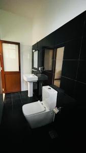 a bathroom with a toilet and a sink at New Stay Inn in Bentota