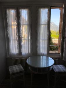 Zimmer mit einem Tisch, 2 Stühlen und 2 Fenstern in der Unterkunft Lake Rooms in Därligen