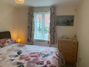 a bedroom with a bed and a dresser and a window at Brimsmore Apartment in Yeovil