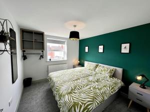 um quarto com uma cama e uma parede verde em Modern 2 Bed House With EV Parking em Henwick