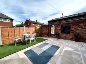 a patio with a table and chairs in a yard at Modern 2 Bed House With EV Parking in Henwick