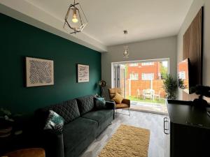 ein Wohnzimmer mit einem Sofa und einer grünen Wand in der Unterkunft Modern 2 Bed House With EV Parking in Henwick
