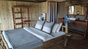 a bedroom with a bed with pillows and a mirror at Zawadi Serengeti camp in Serengeti National Park