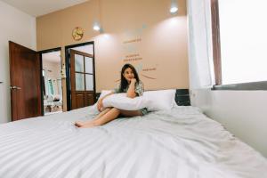 una mujer sentada en una cama con almohadas en Banya BnB ที่พักบ้านย่าบีแอนด์บี เมืองประจวบฯ, en Prachuap Khiri Khan