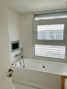 uma banheira branca na casa de banho com uma janela em Modern seafront apartment em Limassol