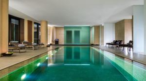 a swimming pool in a hotel lobby with chairs at Bulgari Hotel Milano in Milan