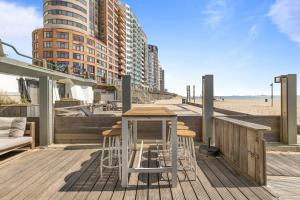 eine Holzterrasse mit einem Tisch und Stühlen am Strand in der Unterkunft Beachrooms Pier 7 in Vlissingen