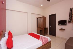 een slaapkamer met een bed met rode kussens en een televisie bij Flagship Hotel Gurukripa in Raipur