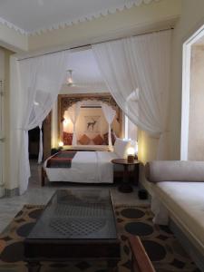 1 dormitorio con 1 cama con cortinas y mesa en The Stepwell Hotel, en Jodhpur