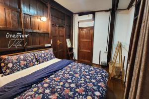 a bedroom with a bed with a blue blanket at V1-Baan Borijinda-Wooden House in The old city of Chiang Mai in Chiang Mai