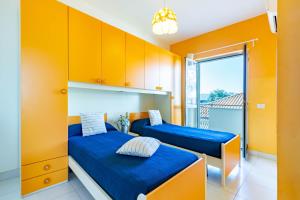 2 camas en una habitación con armarios amarillos en Appartamento Minerva int5 - MyHo Casa en Tortoreto