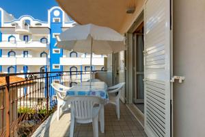 una mesa y sillas en un balcón con sombrilla en Appartamento Minerva int5 - MyHo Casa en Tortoreto