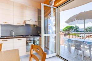 cocina y comedor con mesa y balcón en Appartamento Minerva int5 - MyHo Casa en Tortoreto