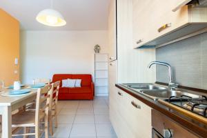 a kitchen with a sink and a table with a couch at Appartamento Minerva int5 - MyHo Casa in Tortoreto Lido