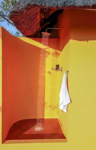 a bathroom with a red and yellow wall with a towel at Yingwe self catering villa bordering Kruger with private pool in Phalaborwa