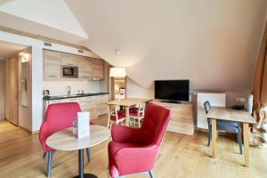 a kitchen and living room with red chairs and a table at Radisson Blu Hotel & Residences in Zakopane