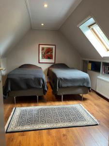 2 bedden in een zolderkamer met een tapijt bij Ruime vakantiewoning in de natuur in Olst
