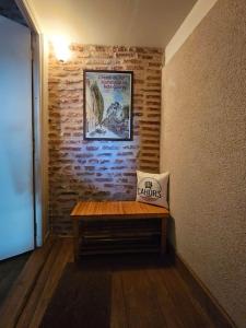 eine Holzbank in einem Zimmer mit Ziegelwand in der Unterkunft Sous les toits du vieux Cahors in Cahors