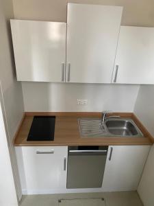 a small kitchen with white cabinets and a sink at Apartment Hafingerweg 11/EG in Sankt Pölten