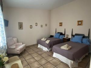 una habitación de hotel con 2 camas y una silla en La del Pozo, en Montánchez