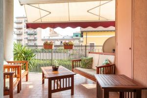 einen Balkon mit Holztischen und Bänken auf einem Gebäude in der Unterkunft Casty Sweet Home - parcheggio privato gratuito in Mailand