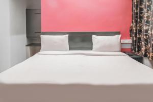 a bedroom with a white bed and a pink wall at OYO Hotel Kota Lodge in Coimbatore