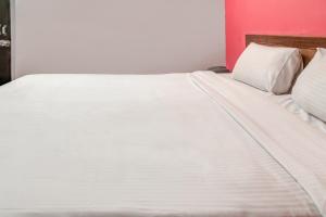 a white bed with white sheets and pillows at OYO Hotel Kota Lodge in Coimbatore