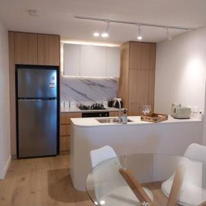 cocina con nevera, mesa y sillas en Stay on Northbourne Ave en Canberra