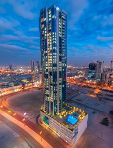 a tall building in a city at night at S Plaza Suites Hotel in Seef