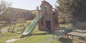 un parque infantil con un tobogán verde en un patio en Petit gîte ou chambre d'hôtes 2/4 personnes, en Buffières