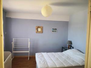 1 dormitorio con cama blanca y pared azul en Petit gîte ou chambre d'hôtes 2/4 personnes, en Buffières