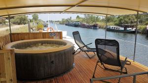 una terraza de madera con 2 sillas y una bañera grande en un barco en PÉNICHE authentique tout confort, en Aigues-Mortes