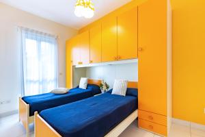 two beds in a room with yellow cabinets at Appartamento Minerva int3 - MyHo Casa in Tortoreto Lido