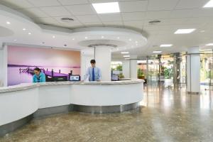 two people standing at a counter in a lobby at Hotel Best Lloret Splash in Lloret de Mar