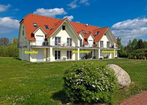 une maison avec un toit rouge sur un champ vert dans l'établissement Gollwitzer Park Musselkieker, à Gollwitz