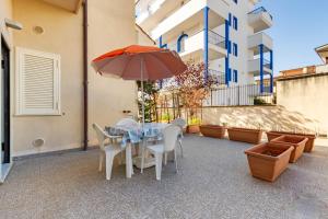 a table and chairs with an umbrella on a patio at Appartamento Minerva int2 - MyHo Casa in Tortoreto Lido