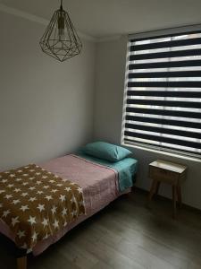 1 dormitorio con cama, mesa y ventana en Hermoso departamento en Iquique